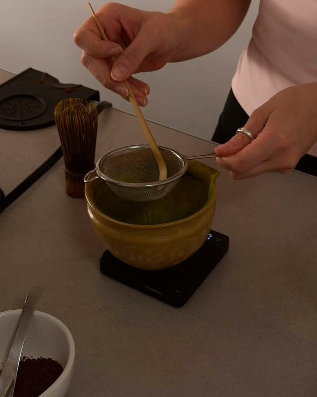 Manos batiendo matcha en un bowl de cerámica